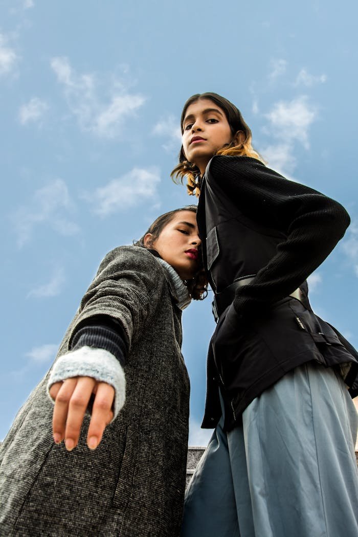 Low-angle Photography of Two Women Standing Under White and Blue Sky